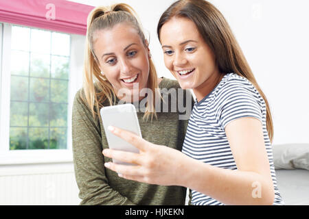 Teenage Girls Reading Text Message On Mobile Phone Banque D'Images