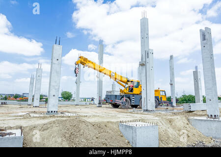 Bras de grue est prêt pour le fonctionnement de l'assemblée de piliers en béton sur nouvel édifice. Banque D'Images