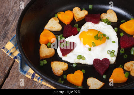 Petit-déjeuner romantique d'œufs frits et légumes en forme de coeur fermer jusqu'à la poêle Banque D'Images