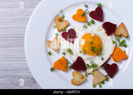 Petit-déjeuner romantique de poêlée de coeurs de légumes et les oeufs dans une assiette. Vue de dessus. Banque D'Images