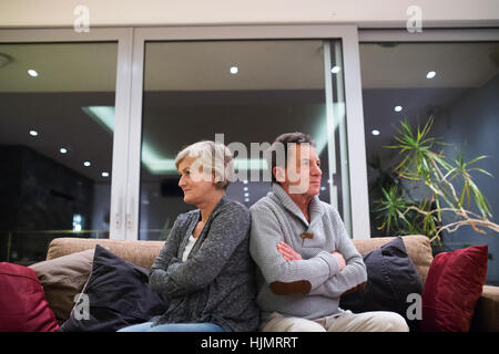 Offensé senior couple sitting on a couch with arms crossed Banque D'Images