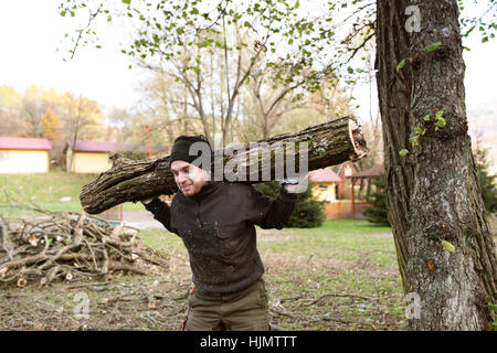 Tronc de l'arbre homme portant sur ses épaules pour le chauffage en hiver. Banque D'Images