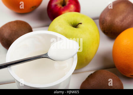 Avec une cuillère de yaourt et de fruits sur la table en bois blanc Banque D'Images