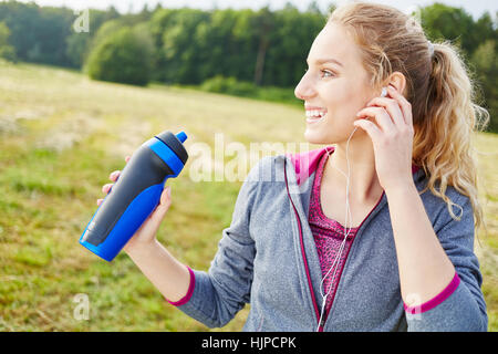 Jeune femme avec de l' eau en bouteille l'eau sourit avec joie Banque D'Images