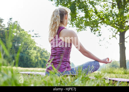 Jeune femme faisant de l'exercice de yoga et méditation en été Banque D'Images