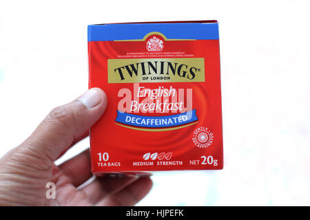 Le petit déjeuner anglais Decaffinated Twinings tenant un plateau dans la main contre isolé sur fond blanc Banque D'Images