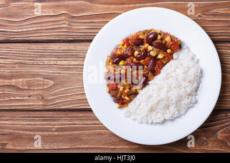 Chili con carne et riz sur une plaque blanche sur un fond de bois horizontale Vue de dessus. Banque D'Images