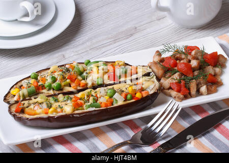 Les moitiés d'aubergines farcies aux légumes et fromage et de viande grillée sur une plaque sur la table Banque D'Images