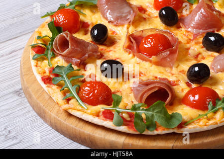 Pizza au jambon prosciutto, tomates, fromage et roquette libre sur fond de bois horizontal. Banque D'Images