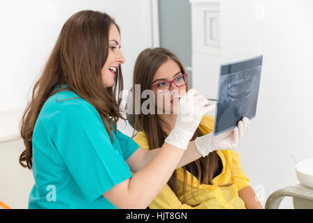 Female dentist showing patient radiographie à rayons x, dans le dentaire Clinc Banque D'Images