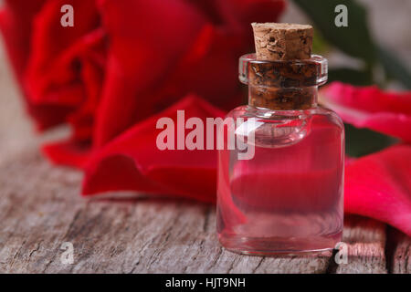 L'eau de rose parfumée dans une bouteille sur une table en bois. Close-up horizontale Banque D'Images