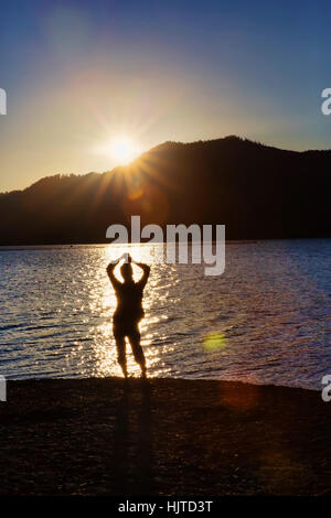 Femme en silhouette sur le lac Quinault beach au coucher du soleil. Olympic National Forest Banque D'Images