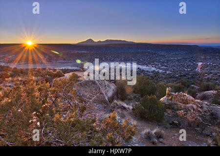 L'aube le soleil, juste une pointe à l'horizon, s'allume une des anciennes tours à main peint Anasazi Pueblo. Banque D'Images