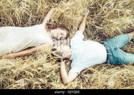 Heureux en amour couple champ de blé jeune couple lying on grass outdoor Banque D'Images