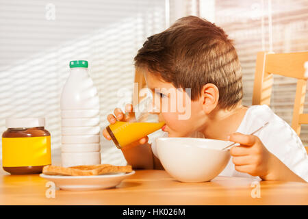 Petit garçon de boire le jus d'orange au petit déjeuner Banque D'Images