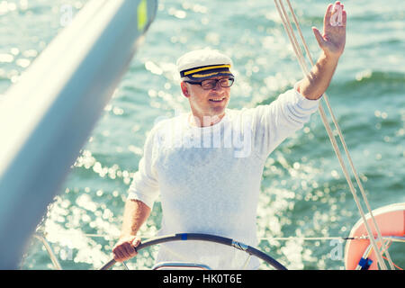 Senior man at helm sur bateau ou yacht de voile en mer Banque D'Images