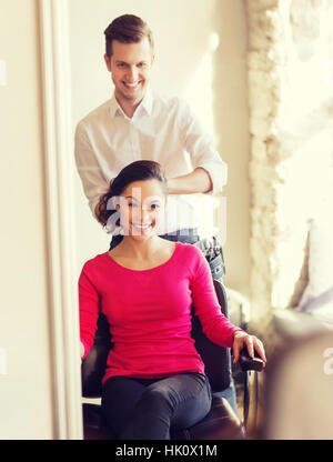 Femme heureuse avec des décisions au salon de coiffure styliste Banque D'Images