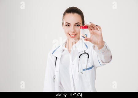 Belle jeune femme Smiling doctor showing bouteille de pilules sur fond blanc Banque D'Images