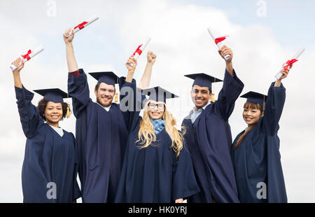 Heureux les étudiants dans les conseils de mortier en agitant des diplômes Banque D'Images