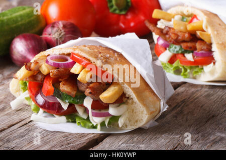 Döner Kebab avec de la viande et légumes dans un pain pita enveloppés dans des close-up sur la table horizontale et d'ingrédients Banque D'Images