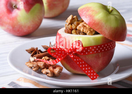 Pomme rouge fraîche farcie aux noix et raisins secs sur une plaque blanche sur la table horizontale, close-up Banque D'Images