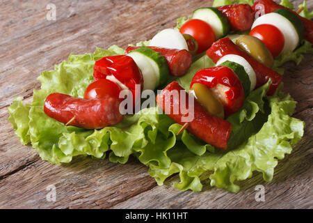 Saucisses grillées avec des légumes sur la laitue sur l'ancienne table libre à l'horizontale. Banque D'Images