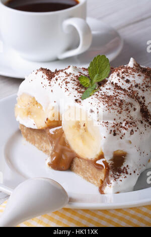 Morceau de gâteau à la banane avec de la crème et du café sur la table verticale. Banque D'Images