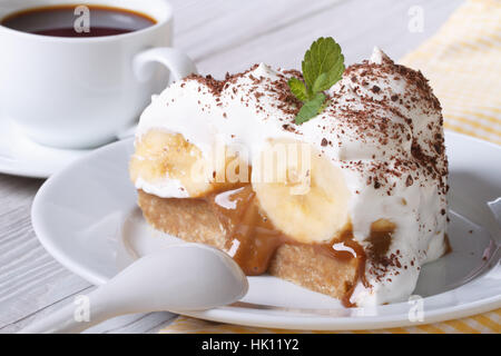 Morceau de gâteau à la banane avec de la crème et du café sur la table horizontale. Banque D'Images