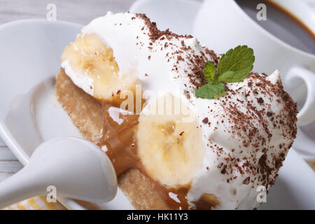 Banoffee pie Slice avec crème et macro café sur la table horizontale. Banque D'Images