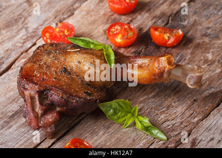 Cuisse de canard rôti au basilic et tomates cerises close up sur une vieille table horizontale Banque D'Images