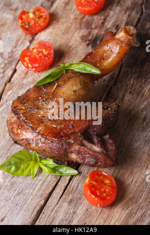 Cuisse de canard rôti au basilic et tomates cerises close up sur une vieille table verticale Banque D'Images