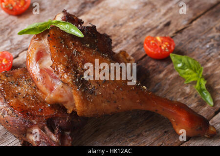 Deux jambes de canard rôti avec tomates close up sur une vieille table de style rustique à l'horizontale. Banque D'Images