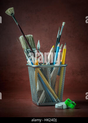 Divers outils de l'artiste et d'accessoires en métal sur fond rouge foncé Banque D'Images