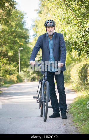 Vieil homme à vélo et casque de vélo. Moment de vie d'été avec des personnes âgées actives personne vivant une vie saine. Banque D'Images