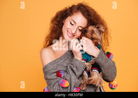 Smiling young woman hugging un chien isolé sur fond orange Banque D'Images