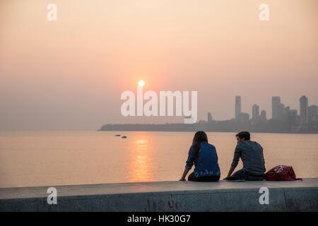 Des couples regarder le coucher de soleil sur Chowpaty Beach à Mumbai (Bombay), Inde. Banque D'Images
