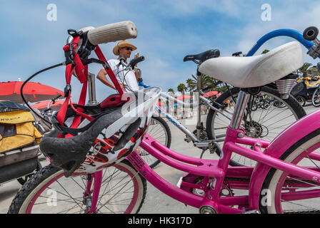 Une partie d'un vélo avec un casque pendant du guidon et un homme sur son portable à Venice Beach, en Californie. Banque D'Images