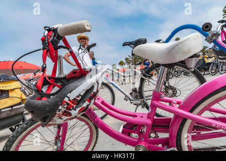 Une partie d'un vélo avec un casque pendant du guidon et un homme sur son portable à Venice Beach, en Californie. Banque D'Images
