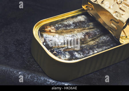 Les sardines en boîte sur fond rustique noir Banque D'Images