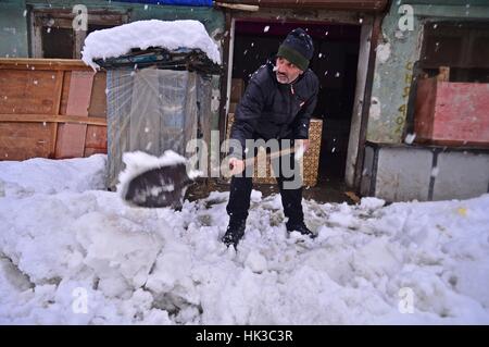 Srinagar, Inde. 25 Jan, 2017. Un commerçant du cachemire neige nettoyage de l'environnement de son magasin à sopore quelques 55 kilomètres de Srinagar, la capitale d'été du Cachemire sous contrôle indien : Eeshan Crédit Peer/Pacific Press/Alamy Live News Banque D'Images