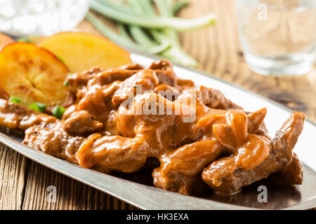 Bœuf Stroganoff, recette originale de plats russes. De fines lamelles de boeuf cuit dans la crème et la pâte de tomates, servi avec pommes de terre croquantes Banque D'Images