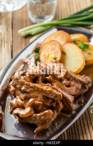 Bœuf Stroganoff, recette originale de plats russes. De fines lamelles de boeuf cuit dans la crème et la pâte de tomates, servi avec pommes de terre croquantes Banque D'Images