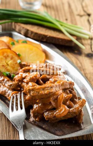 Bœuf Stroganoff, recette originale de plats russes. De fines lamelles de boeuf cuit dans la crème et la pâte de tomates, servi avec pommes de terre croquantes Banque D'Images