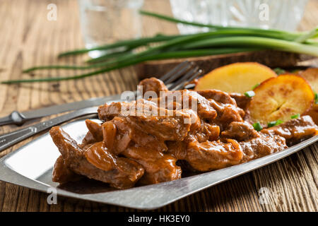 Bœuf Stroganoff, recette originale de plats russes. De fines lamelles de boeuf cuit dans la crème et la pâte de tomates, servi avec pommes de terre croquantes Banque D'Images