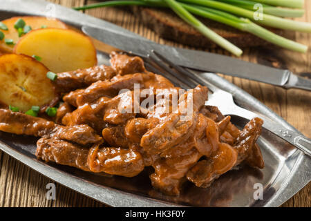 Bœuf Stroganoff, recette originale de plats russes. De fines lamelles de boeuf cuit dans la crème et la pâte de tomates, servi avec pommes de terre croquantes Banque D'Images