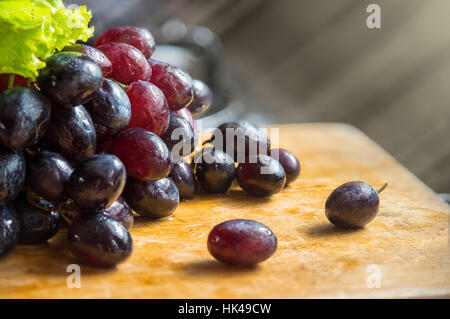 Bande de rouge, noir, violet raisin jeter sur tables en bois avec rayon lumineux background, selective focus Banque D'Images