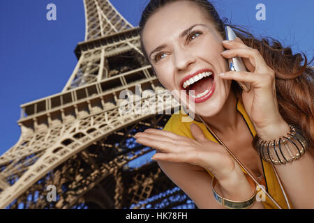 Touristique, sans doute, mais pourtant si amusant. surprised young woman talking on a mobile phone dans l'avant de la tour Eiffel à Paris, France Banque D'Images