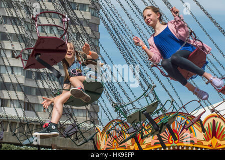 Deux adolescentes assis sur le carrousel avec une tour en arrière-plan sur le parc Dreamland, Margate, Kent. Banque D'Images