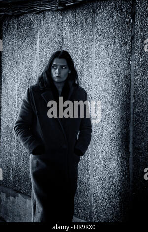 Une femme marche nerveux par un passage souterrain dans un style film noir Banque D'Images