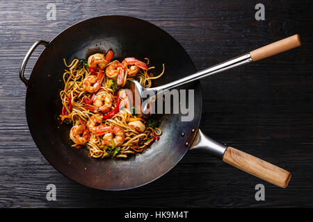 Sauté de nouilles Udon aux crevettes et légumes au wok casserole sur fond de bois brûlé noir Banque D'Images